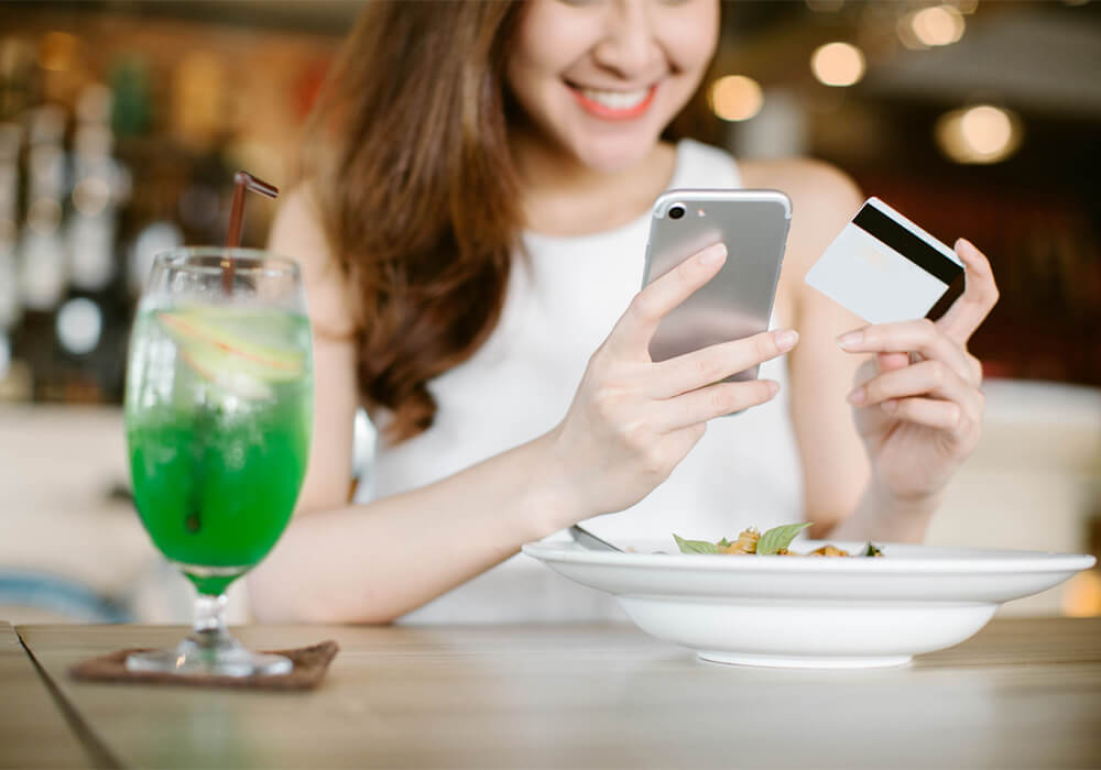Diner paying with credit card at the table on smartphone