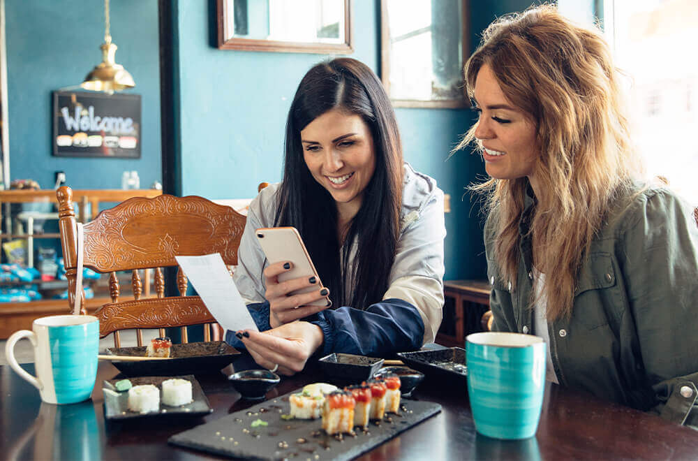 2 Diners looking at receipt while one scans it with their smartphone