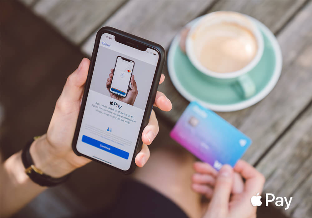 Apple Pay logo and diner with smartphone and credit card in hand