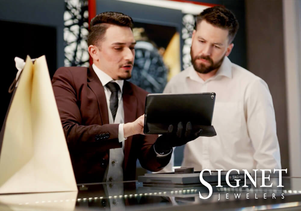 Signet Jewler logo associate and customer looking at tablet together
