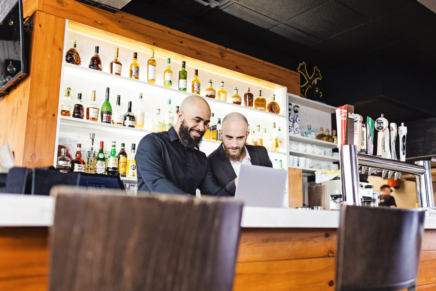 Bar Managers with POS and integrations looking at laptop